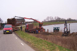 Het aangeleverde vulmateriaal wordt overgeladen op de boot om verder naar de werkplaats vervoerd te worden